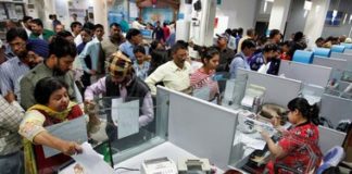 People stand in queues at cash counters to deposit and withdraw money inside a bank in Chandigarh