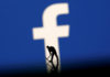 A figurine is seen in front of the Facebook logo in this illustration